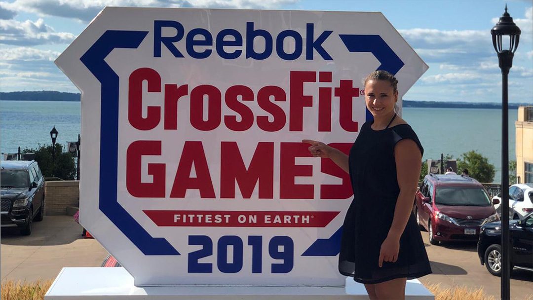 Lisa Eble zeigt auf das Crossfit Games Logo